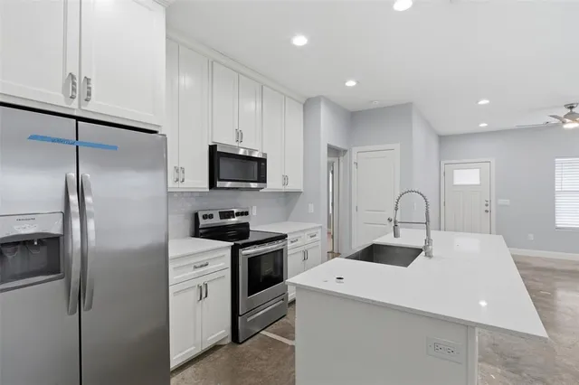 a kitchen with a sink stainless steel appliances and white cabinets