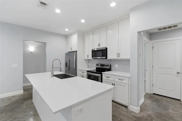 a kitchen with sink a microwave and cabinets
