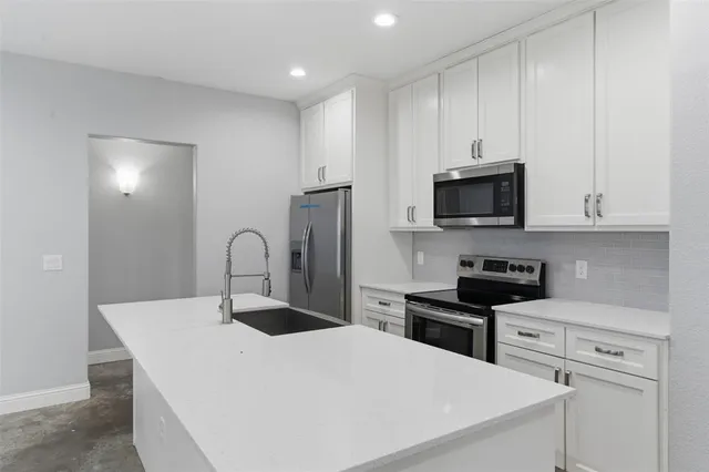 a kitchen with stainless steel appliances a white stove top oven and white cabinets