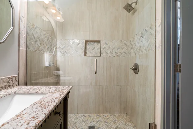 a bathroom with a granite countertop shower a sink and a mirror