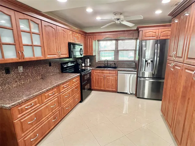 a kitchen with stainless steel appliances granite countertop a refrigerator a stove top oven a sink and dishwasher