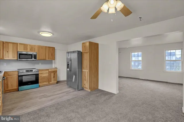 a large kitchen with stainless steel appliances granite countertop a refrigerator a stove a sink dishwasher a oven with white cabinets and wooden floor