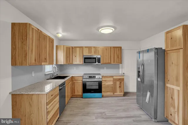 a kitchen that has a lot of cabinets in it and stainless steel appliances