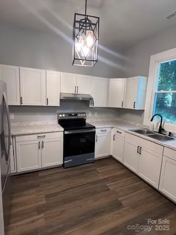 a kitchen with stainless steel appliances granite countertop a stove a sink and white cabinets