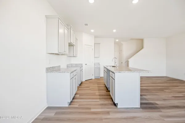 a kitchen with kitchen island sink and white cabinets