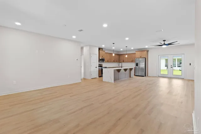 a large kitchen with stainless steel appliances kitchen island a large counter top and a chandelier