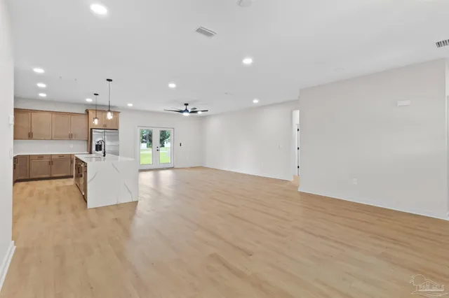 a view of kitchen with kitchen island white cabinets stainless steel appliances with wooden floor and view living room