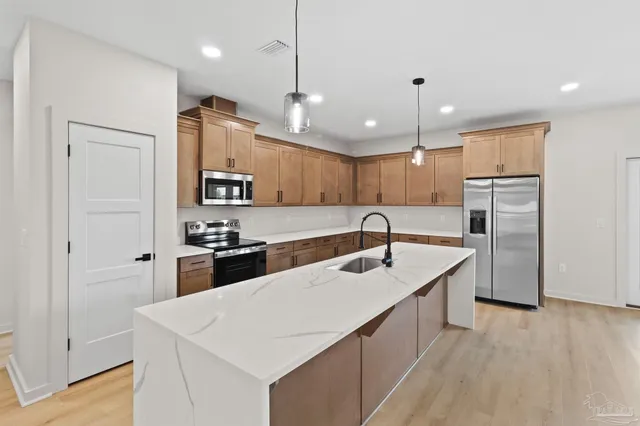 a kitchen with stainless steel appliances granite countertop a sink a stove and a wooden floors
