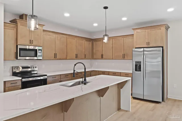 a large kitchen with stainless steel appliances kitchen island granite countertop a sink stove and refrigerator