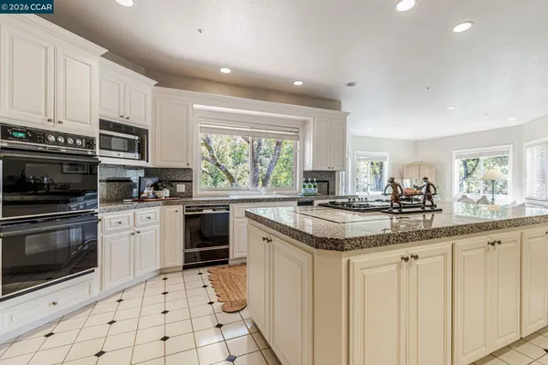 a kitchen with granite countertop white cabinets white appliances and sink