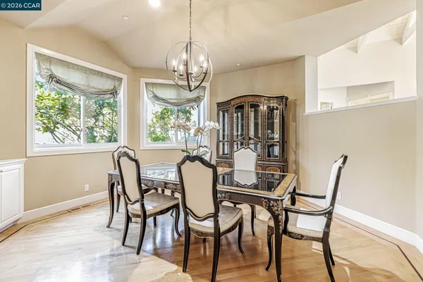 a view of a dining room with furniture a chandelier and large windows