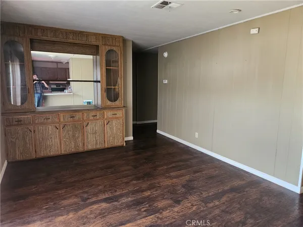 a view of a hallway to a room with wooden floor and cabinet