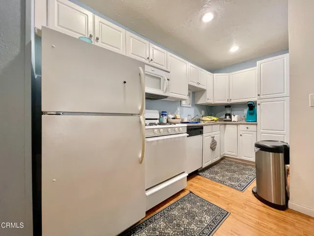a kitchen with stainless steel appliances granite countertop a refrigerator sink and white cabinets