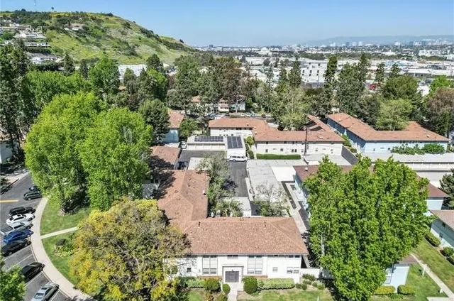 an aerial view of residential houses with outdoor space and trees