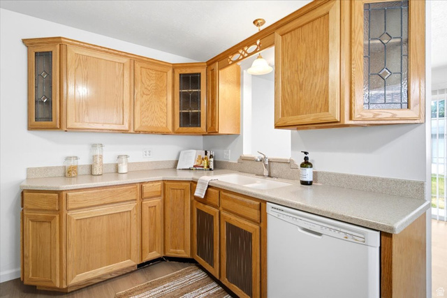 1341 29th Street Ogden, UT 84403 - Photo 10 of 37 L-shaped kitchen featuring wood cabinetry, integrated white sink, dishwasher, and light-toned countertops