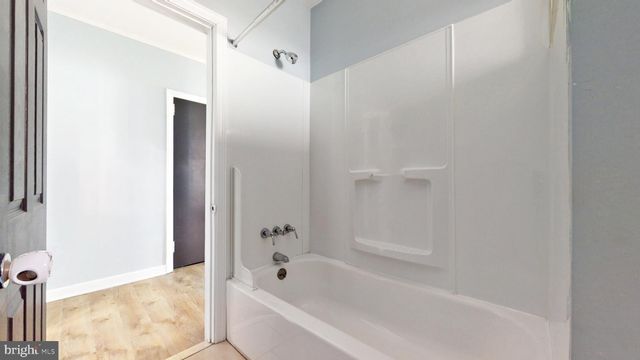 an empty room with wooden floor cabinet and windows