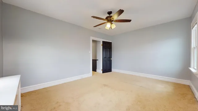 a view of an empty room with chandelier fan and fire place