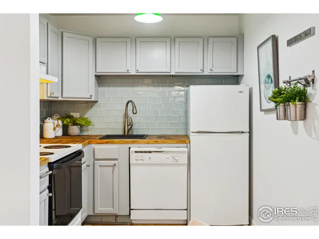 a kitchen with stainless steel appliances granite countertop a refrigerator a sink a stove and white cabinets