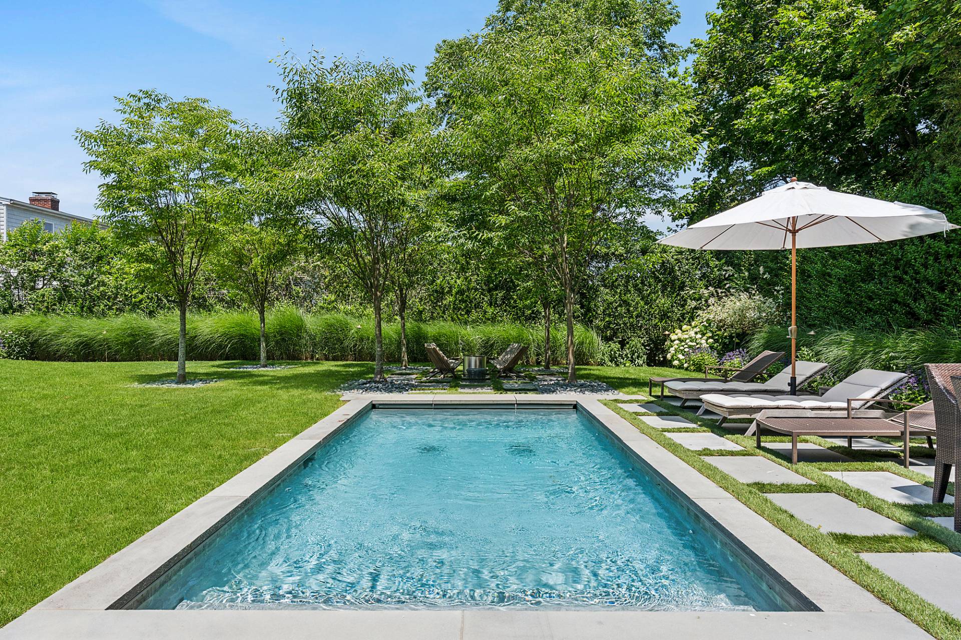8 Fresh Pond Road Sag Harbor, NY 11963 - Photo 6 of 40 a view of a swimming pool with lawn chairs under an umbrella