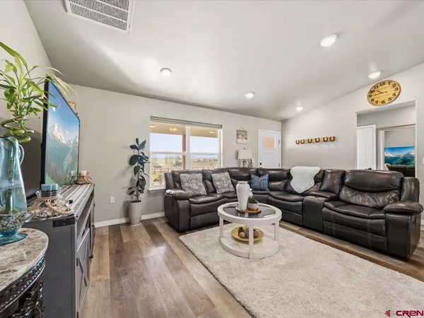 a living room with furniture kitchen view and a wooden floor