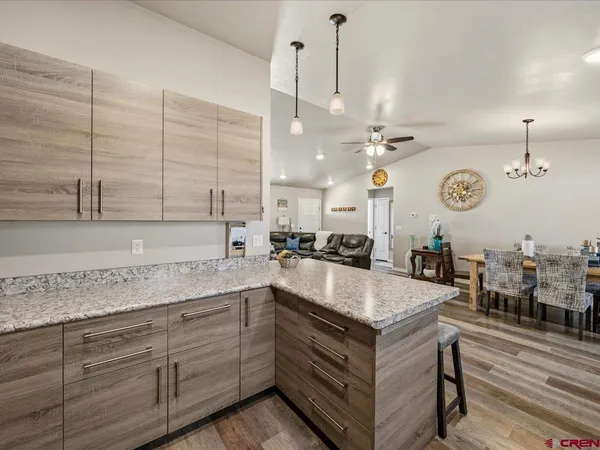 a large kitchen with kitchen island a stove a sink dishwasher and white cabinets with wooden floor