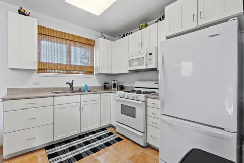 a kitchen with granite countertop white cabinets and white appliances