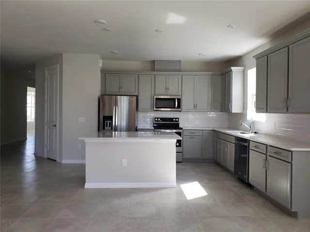 a kitchen with stainless steel appliances a sink a stove a refrigerator cabinets and a window