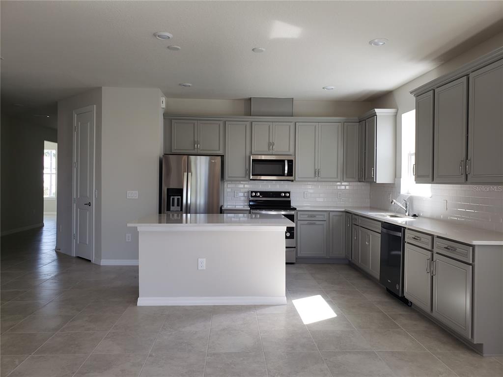 17244 Cagan Crossings Boulevard Clermont, FL 34714 - Photo 2 of 14 a kitchen with stainless steel appliances a sink a stove a refrigerator cabinets and a window