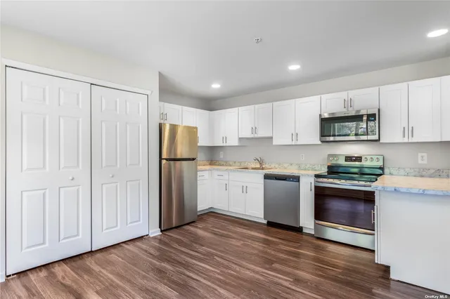 a kitchen with granite countertop white cabinets and stainless steel appliances