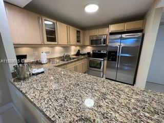 a kitchen with stainless steel appliances granite countertop a sink stove microwave and refrigerator