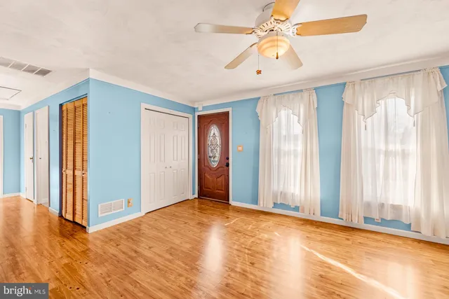 a view of an empty room with window and a kitchen