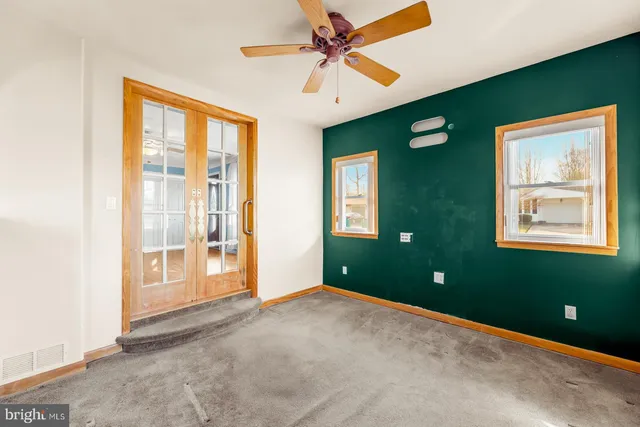 a view of an empty room with window and a ceiling fan