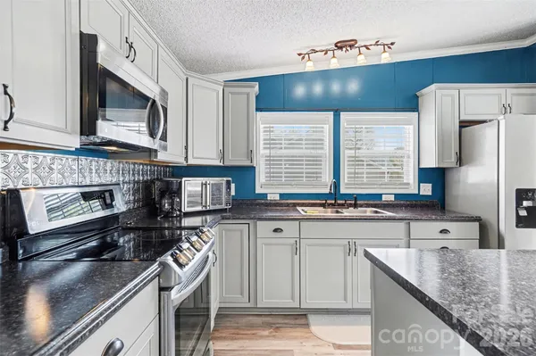 a kitchen with stainless steel appliances granite countertop a sink stove and cabinets