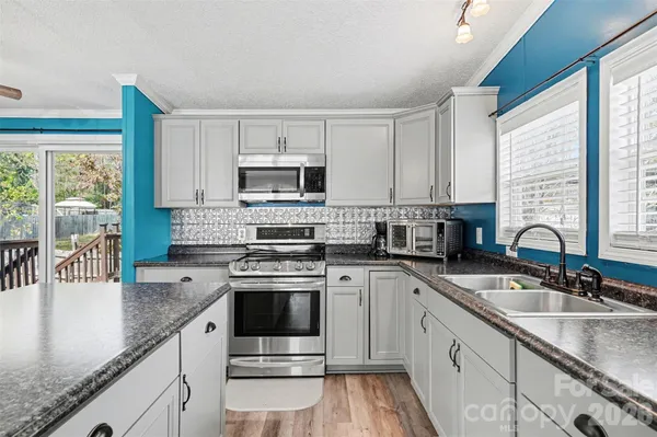 a kitchen with stainless steel appliances granite countertop a sink dishwasher and a refrigerator with wooden floor