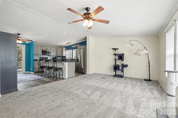 a view of a livingroom with a fireplace a ceiling fan and windows