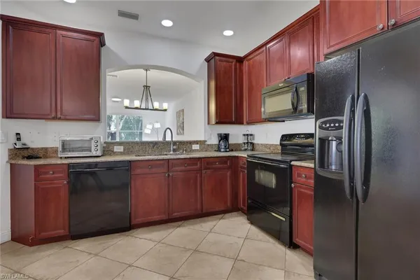 a kitchen with stainless steel appliances granite countertop a refrigerator a stove a sink and a microwave