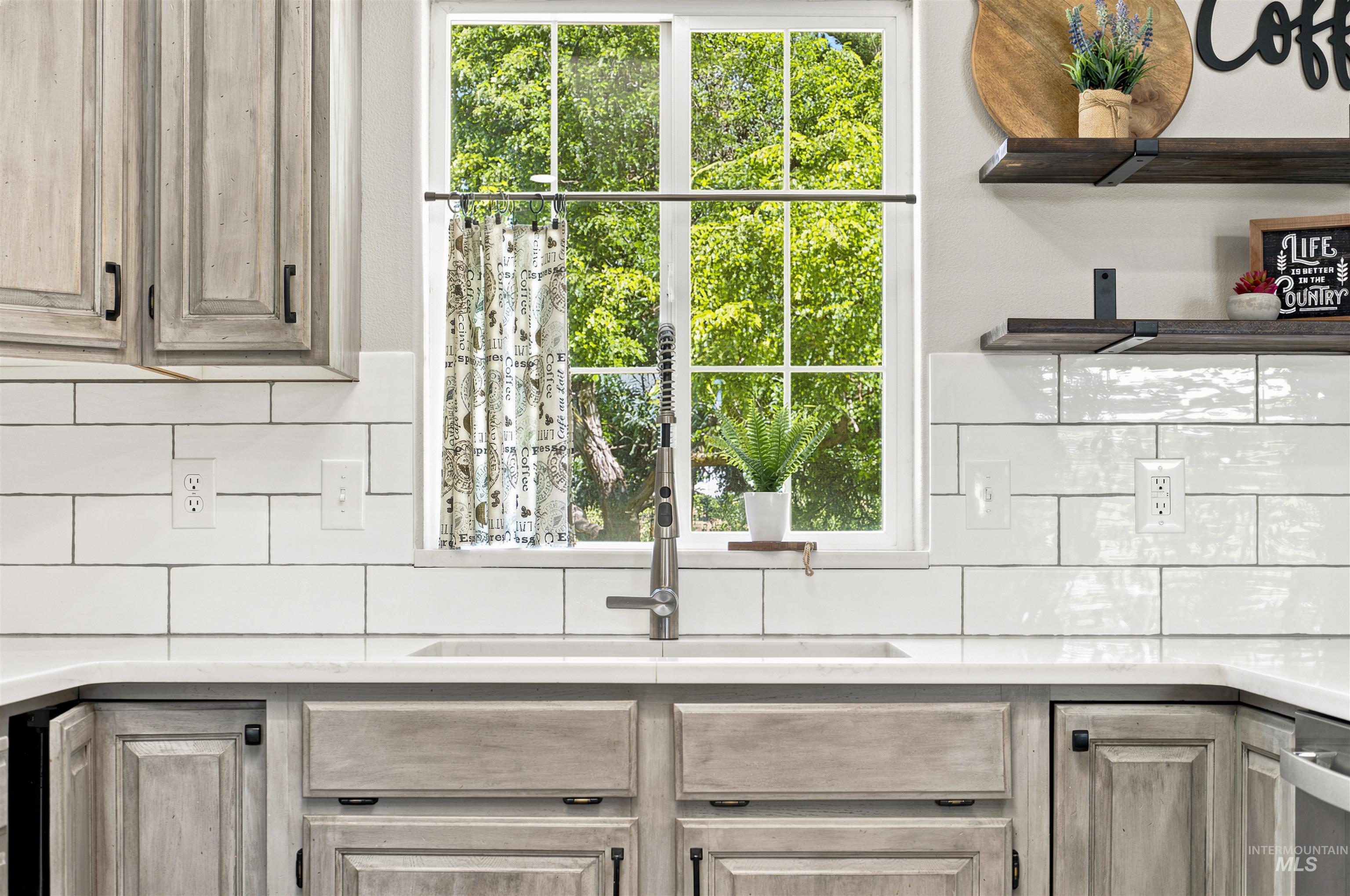 24864 Coventry Drive Caldwell, ID 83607 - Photo 13 of 49 Kitchen featuring white subway tile backsplash, light-toned wood-finish cabinetry, a window with exterior tree views, a stainless steel faucet, and open shelving