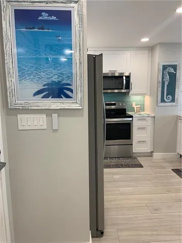 a view of a refrigerator in kitchen and an empty room