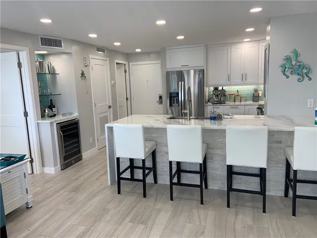 a kitchen with stainless steel appliances kitchen island granite countertop a dining table chairs and refrigerator