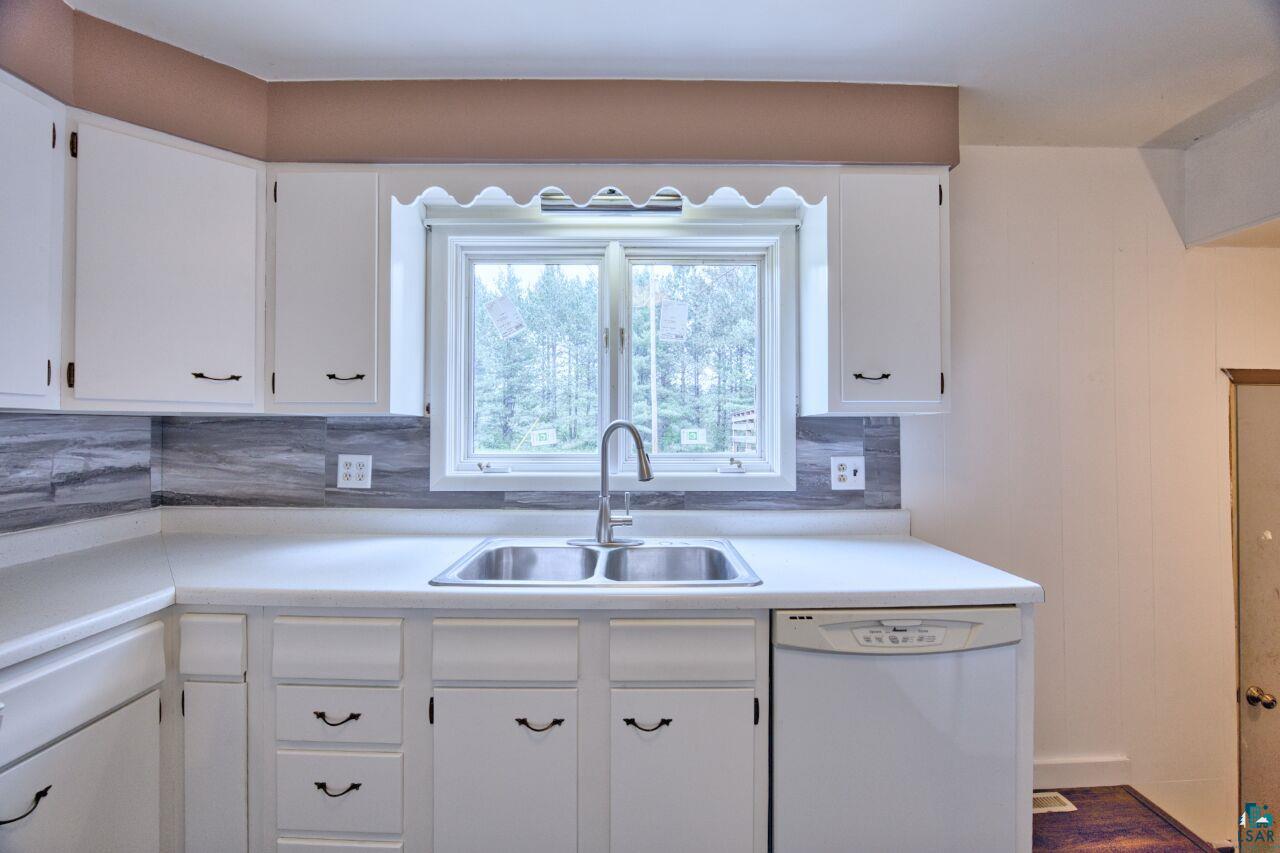 4755 Judd Road Gilbert, MN 55741 - Photo 8 of 50 Kitchen featuring dishwasher, a sink, white cabinets, and light countertops