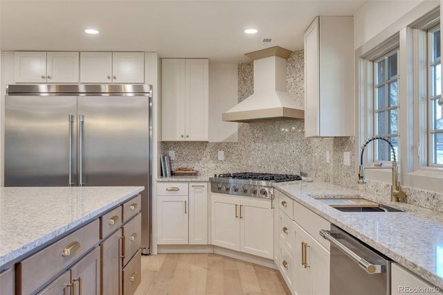 a kitchen with stainless steel appliances granite countertop a sink a stove and a refrigerator