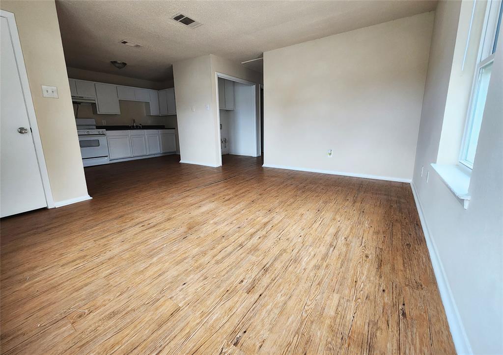 4304 South Cravens Road Fort Worth, TX 76119 - Photo 1 of 21 Unfurnished living room with sink, a textured ceiling, and light wood-type flooring