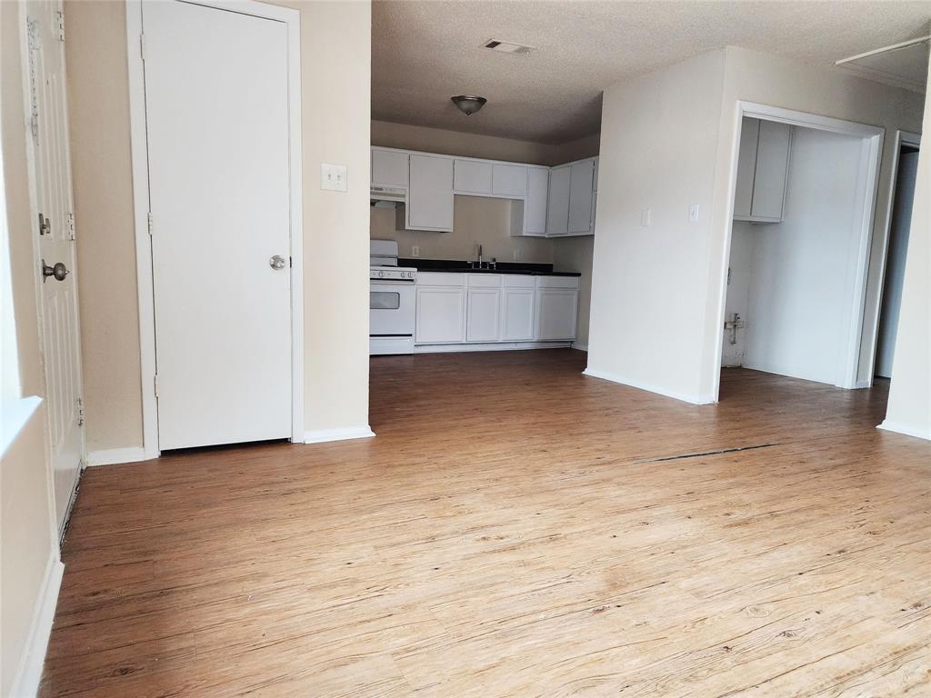 4304 South Cravens Road Fort Worth, TX 76119 - Photo 2 of 21 Kitchen with white range with gas stovetop, white cabinets, a textured ceiling, and light hardwood / wood-style flooring