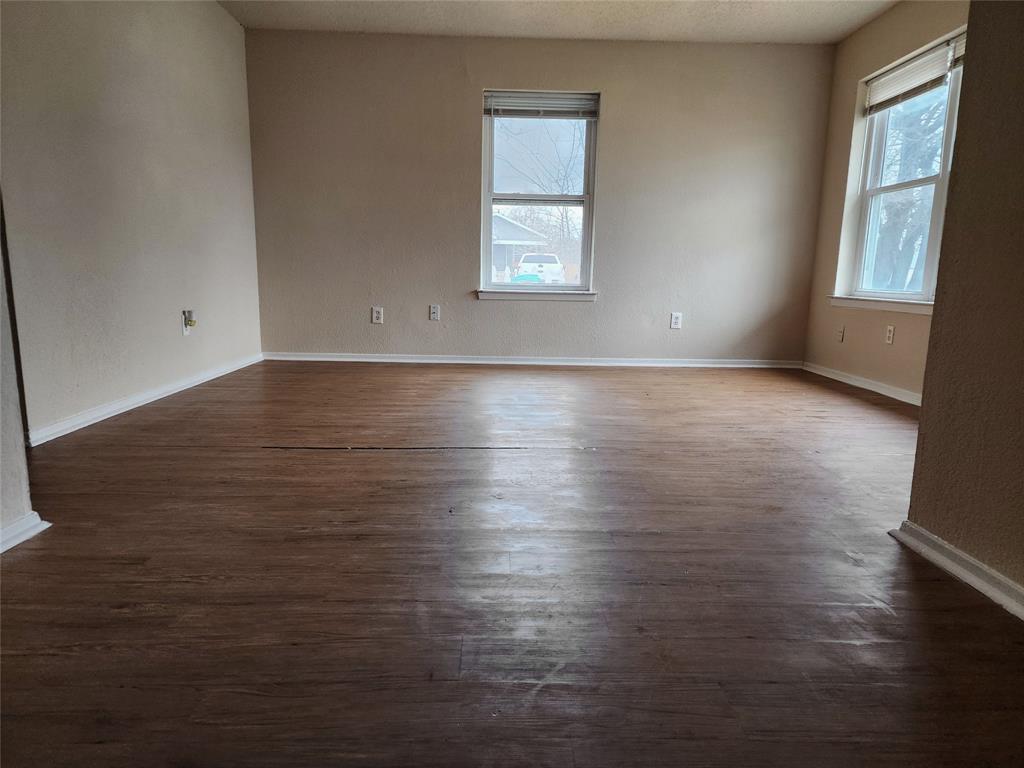 4304 South Cravens Road Fort Worth, TX 76119 - Photo 7 of 21 Unfurnished room with a wealth of natural light and dark hardwood / wood-style flooring