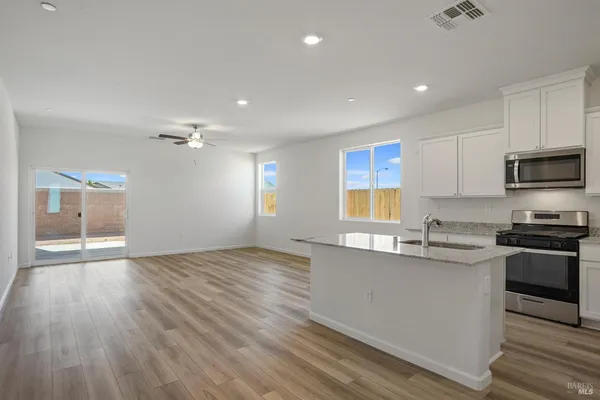 a kitchen with stainless steel appliances granite countertop a sink cabinets and wooden floor