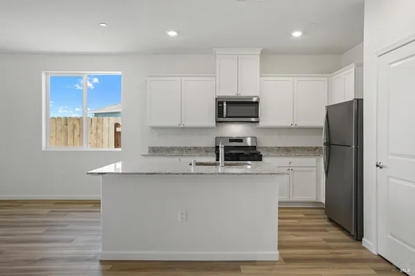 a kitchen with stainless steel appliances a refrigerator a sink and white cabinets