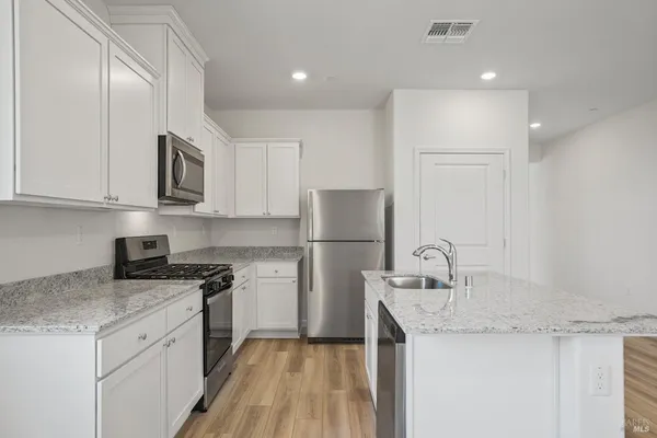 a kitchen with a sink a stove a refrigerator and cabinets