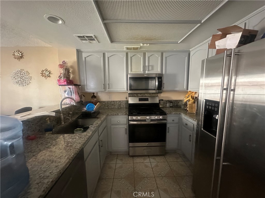5147 Moonraker Road Palmdale, CA 93552 - Photo 6 of 21 a kitchen with granite countertop a refrigerator stove and sink