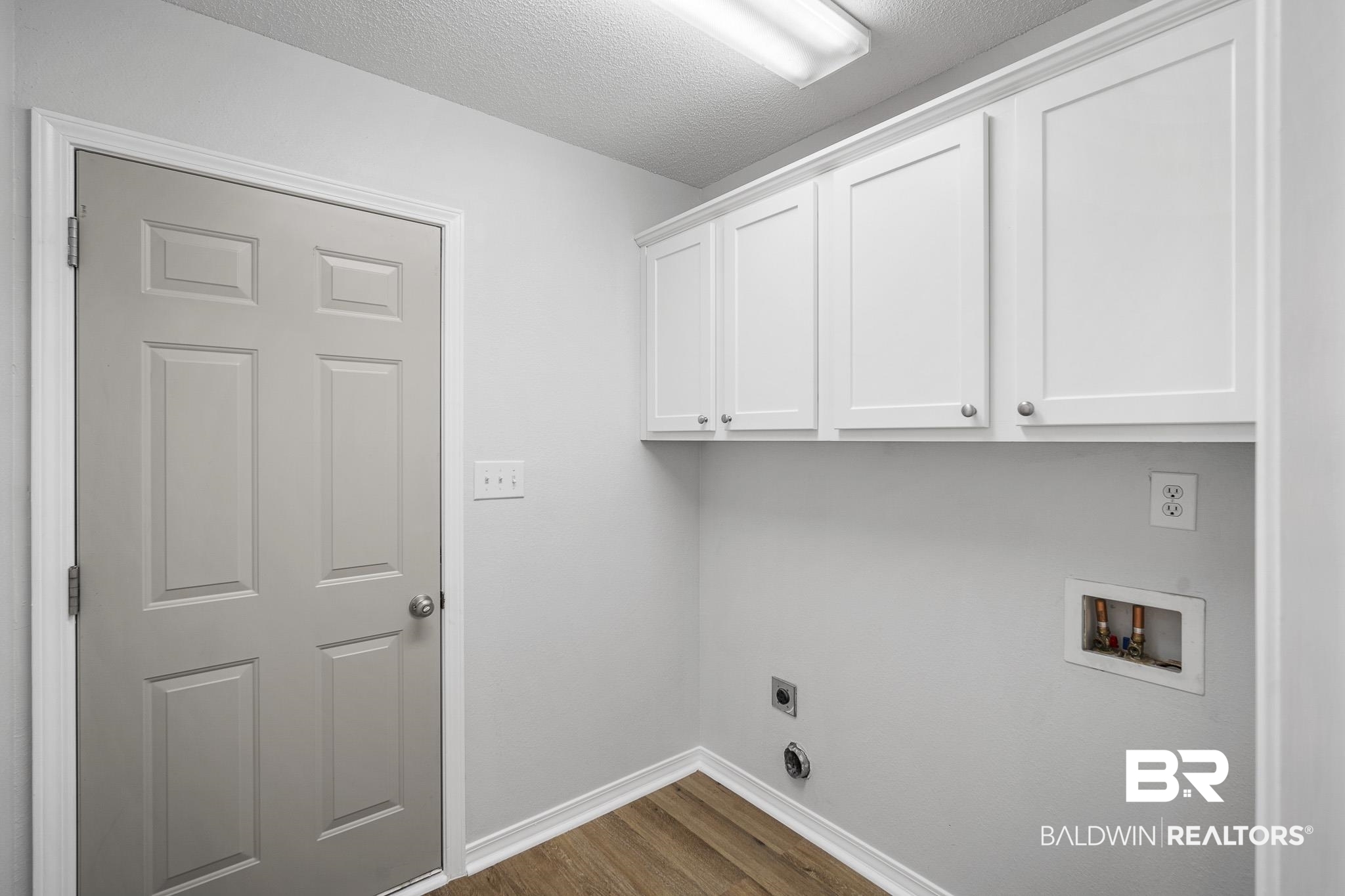 9814 Woolrich Avenue Fairhope, AL 36532 - Photo 14 of 29 Washroom featuring hookup for an electric dryer, a textured ceiling, dark hardwood / wood-style flooring, hookup for a washing machine, and cabinets