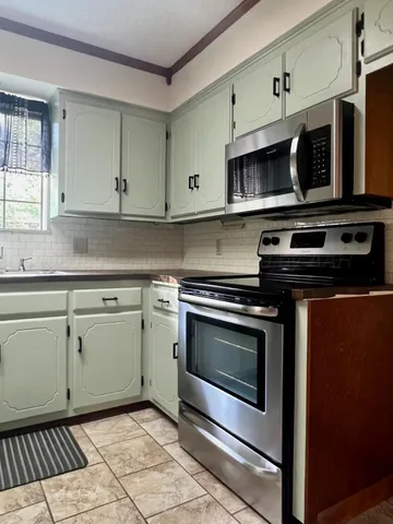 a kitchen with stainless steel appliances granite countertop a stove microwave and cabinets